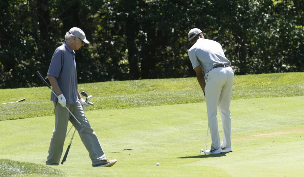 Obama prende la mira sotto lo sguardo attento di Larry David, noto attore e produttore cinematografico statunitense. REUTERS